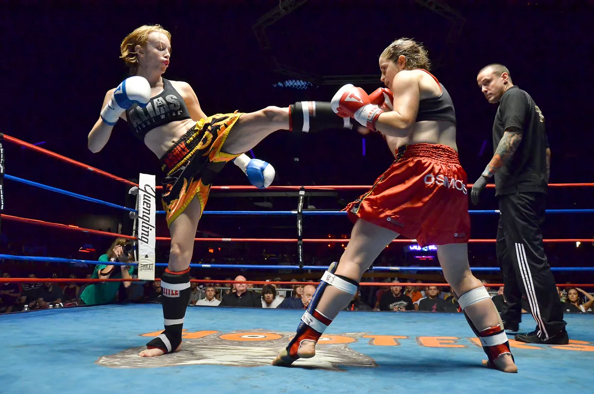 Deux combattantes de Muay Thaï échangent des coups sous les projecteurs d’un ring