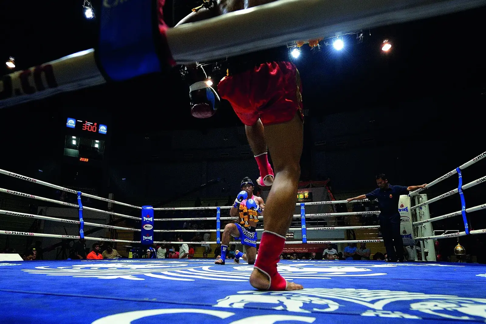 Ring du Lumpinee un soir de combats : un boxeur s’avance, l’adversaire salue à genoux